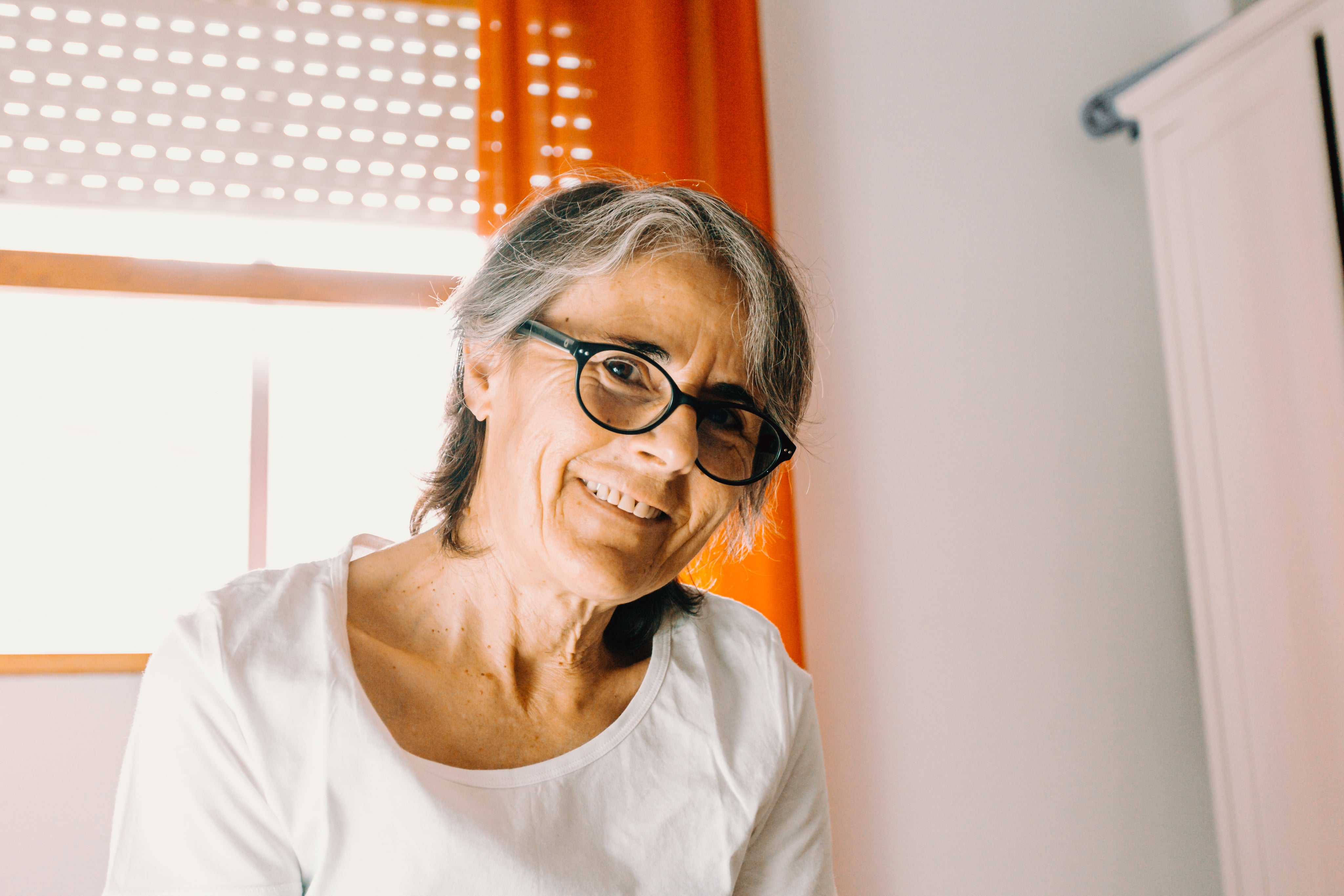 files/woman-smiling-to-the-camera-with-orange-curtains-behind.jpg